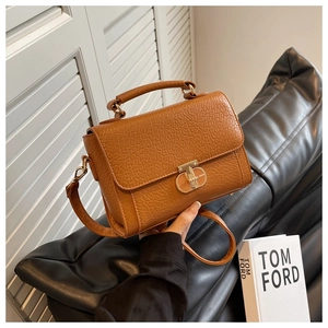 Détail d'un petit sac carré en cuir marron texturé avec fermoir doré et bandoulière
