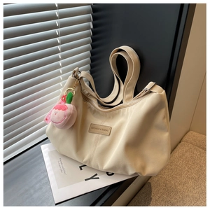 Detail of beige nylon pleated dumpling bag featuring a cute peach pendant and leather label