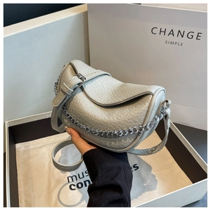 Detalle de bolso silla en cuero granulado gris claro con cadena de plata y funda de tela