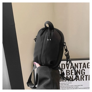 Close-up of black mini crossbody bag with unique vertical zipper and patterned rope strap