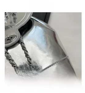 Detail of silver metallic textured bucket bag with metal turn-lock and chain strap