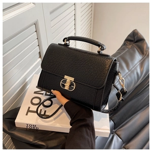 Détail du sac à main noir en cuir crocodile avec fermoir en métal doré en forme de T