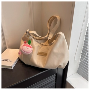 Detail of off-white nylon crescent bag with leather patch and pink peach plush charm