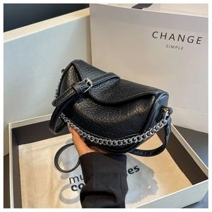 Detalle de bolso tipo montura en cuero granulado negro con cadena de metal plateada gruesa