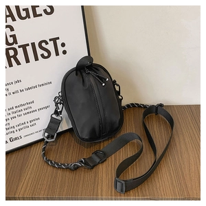 Detail of a black nylon crossbody bag with adjustable strap on a wooden surface