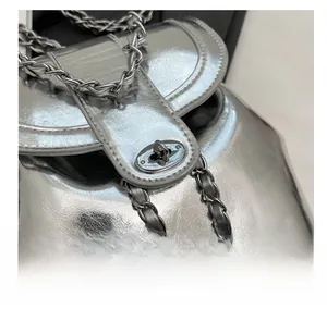 Close-up of bright silver metallic chain bag featuring a polished metal twist lock