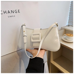 Detail of white crocodile embossed underarm bag with large square buckle and adjustable strap