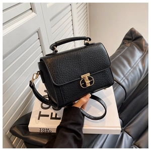 Détail du sac bandoulière noir avec fermoir géométrique doré et poignée supérieure