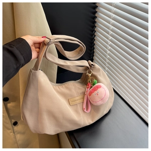 Detail of beige nylon half-moon crossbody bag with adjustable strap and peach charm