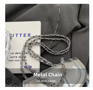 Detail show of woven metal chain strap on a modern silver bucket bag with mirror finish