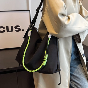 Large black nylon hobo bag with neon green rope detail shown on a model in a trench coat