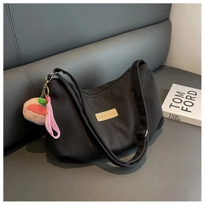 Detail of black nylon crossbody bag with a cute peach plush charm and fashion brand label