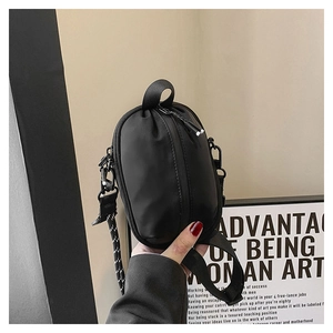 Detail of minimalist black nylon mini crossbody bag with top handle and vertical zipper