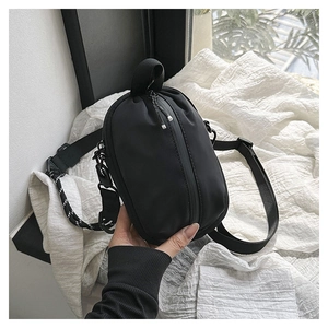 Detail of waterproof black nylon crossbody bag featuring vertical zipper and quick release buckle