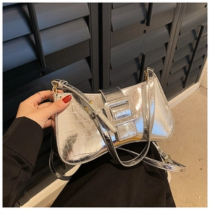 Close-up of silver crocodile embossed shoulder bag with metallic buckle and strap detail