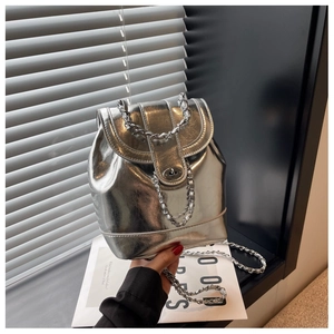 Close-up of silver metallic bucket bag with chain strap and glossy flap buckle detail