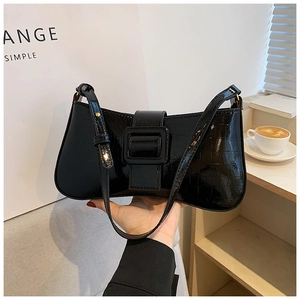 Close-up of black glossy crocodile pattern underarm bag with decorative buckle