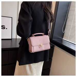 Détail du sac à main rose en cuir texturé avec un fermoir rotatif doré sur le côté