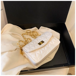 Détail du sac matelassé blanc avec fermoir doré dans un emballage cadeau élégant