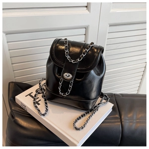 Detail of glossy black chain backpack featuring metal twist lock on white props
