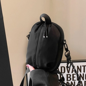Minimalist black nylon crossbody bag with vertical zipper and adjustable strap