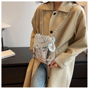 Detail of a silver metallic mini backpack featuring chain straps and a rotary lock clasp