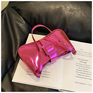 Detail view of fuchsia croc-embossed underarm bag with metallic texture and large buckle