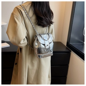 Close-up of metallic silver backpack with chain straps worn over a beige coat