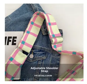 Detail of adjustable canvas strap with pink checkered pattern and silver metal buckle