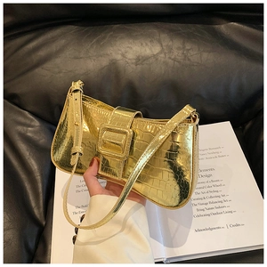 Detail of gold faux crocodile texture underarm bag with decorative metal buckle
