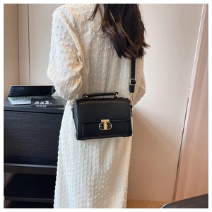 Détail du sac à main en cuir noir avec fermoir en T doré et poignée élégante