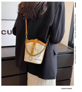 Detail of lychee textured leather bucket bag with metallic chain and brand logo