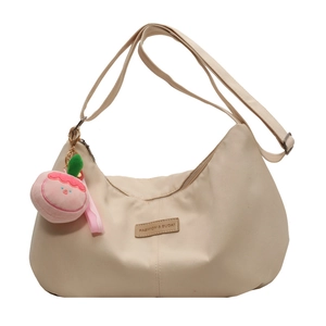 Chic beige nylon crescent bag with adjustable strap and peach plush charm decoration