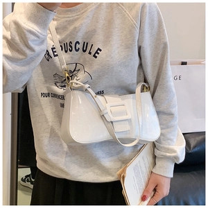 Detail of white patent leather underarm bag with large square buckle on a shoulder strap