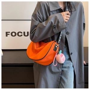 Detailed view of orange nylon crescent bag with adjustable strap and peach pendant