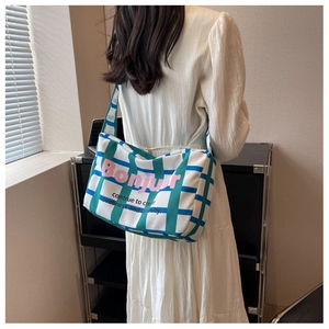 Detail of canvas crossbody bag with green grid pattern and pink Bonjour lettering