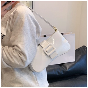 Detail of white crocodile embossed patent leather baguette bag with large square buckle design