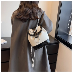Detailed view of bicolor chain bucket backpack with metal twist lock on grey coat