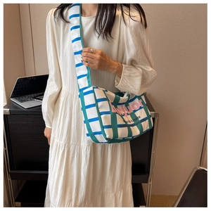 Detail of canvas bag featuring blue and green stripes with pink Anijuor brand lettering