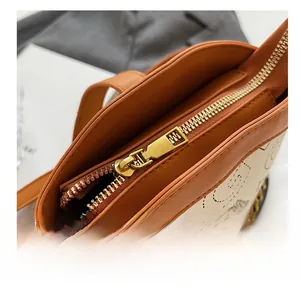 Detail shot of the golden zipper and luxury chain on this brown leather bucket bag
