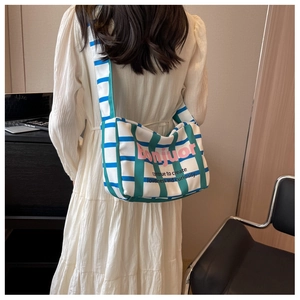 Rear view of canvas crossbody bag with green plaid patterns and pink Bonjour slogan
