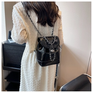 Detail of black patent leather backpack with silver chain straps and turn-lock closure