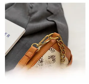 Detail of vintage gold lobster clasp and chain on a cream leather bucket bag