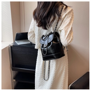 Detail of glossy black chain backpack with metallic twist lock on a modern office desk