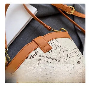 Detailed close-up of premium stitching on cream litchi leather bucket bag with gold hardware