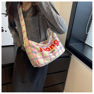 Detail of colorful plaid canvas crossbody bag with wide shoulder strap and red lettering