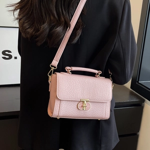 Petit sac rose grainé avec boucle dorée porté par un mannequin en blazer noir