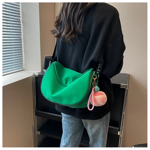 Detail view of a bright green crescent bag with a cute pink peach plush charm
