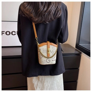 Detail of monogram bucket bag with gold chain strap shown on model for scale