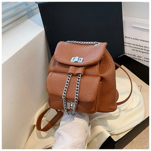 Detalle de mochila de cuero marrón con patrón litchi, cadena plateada y cierre de giro